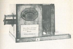 Erste nach Deutschland gelangte Originalkamera von Daguerre: Das Kameragehäuse besteht aus zwei ineinandersteckenden, verschiebbaren Holzkästen zur Scharfeinstellung des Motivs. Eine einfache Metallklappe verschließt das stark abgeblendete Objektiv, dass aus einer einfachen achromatischen Linse besteht. Diese Kamera befindet sich heute im Deutschen Museum, München.