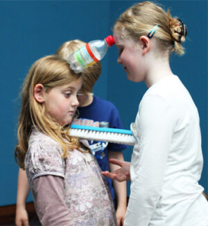 Michelle und Hanna kennen sich inzwischen recht gut und können sich aufeinander verlassen: Eine Minute lang haben sie gemeinsam für die Anweisung „Organisation von Liebe“ Objekte balanciert.