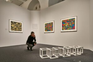 Ausstellungsansicht "In die dritte Dimension" mit Sol LeWitts "Maquette for Seven Cubes Half Off" (1990, Holz, weiß bemalt) und den Linolschnitten der Serie "Distorted Cubes" (2001), alle Werke © VG Bild-Kunst, Bonn 2017